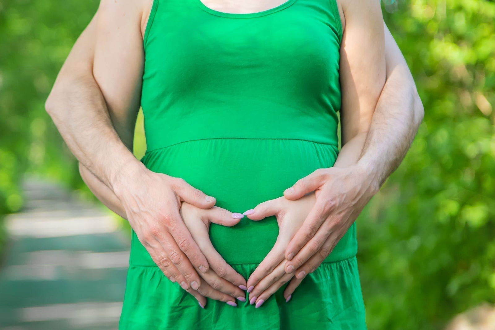 Primavera y fertilidad: La influencia de la luz y el bienestar en la concepción Blog Bionatis Suplementos foto de pareja irreconocible embarazada mujer al frente tocando barriga manos en forma de corazón