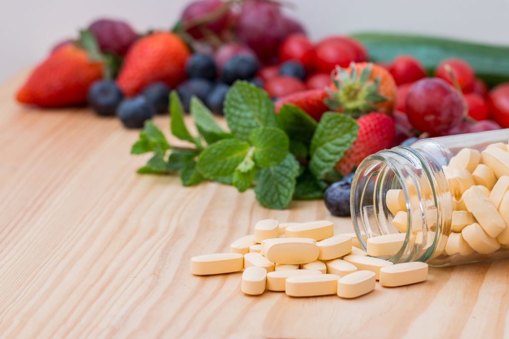El papel del multivitamínico en la fertilidad femenina fotografía de frutas y verduras y pastillas píldoras multivitamínico sobre una mesa Bionatis